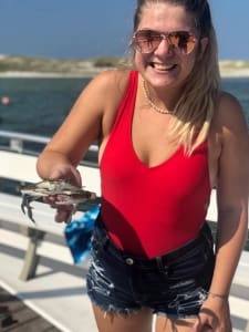 image of a woman holding a crab found during an island time sailing trip