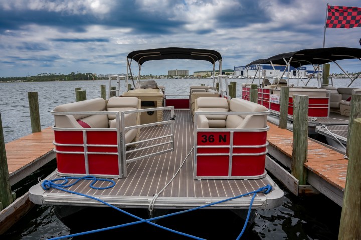 Red pontoon boat docked with cloudy sky in the background.