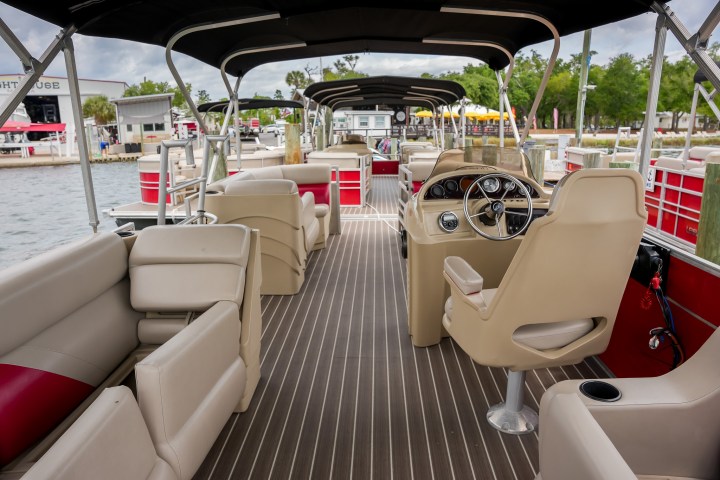 Interior of a pontoon boat with seating and a steering console.