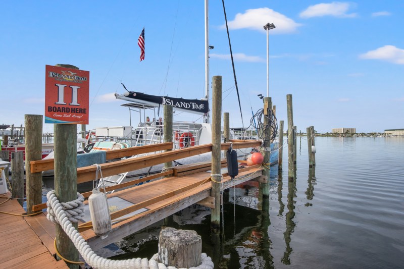Boat docked at a marina with wooden ramp and American flag in the background.