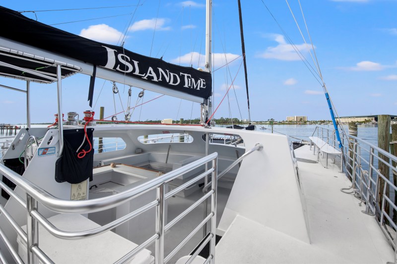 Deck of a catamaran named 'Island Time' docked in a marina with clear blue skies.