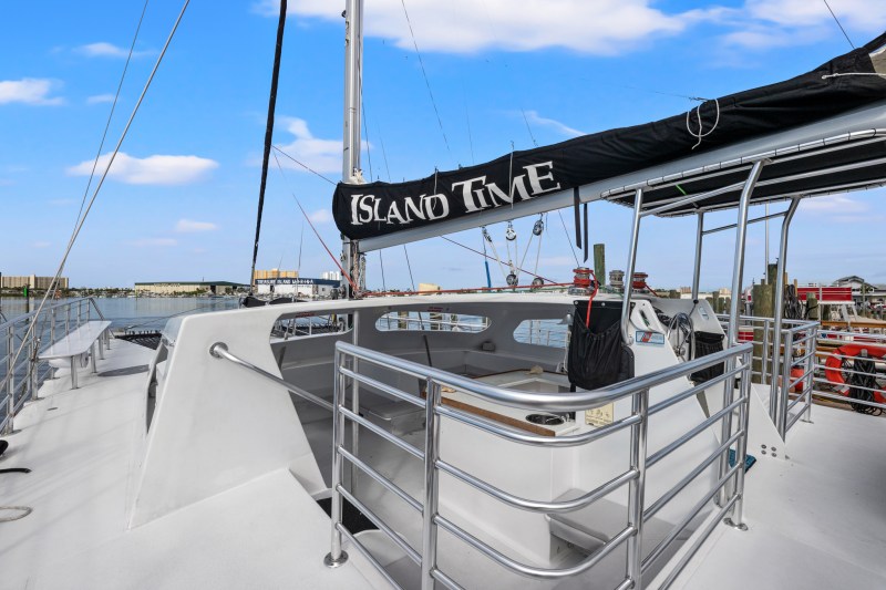 Sailboat 'Island Time' docked, showing deck and helm under clear sky.