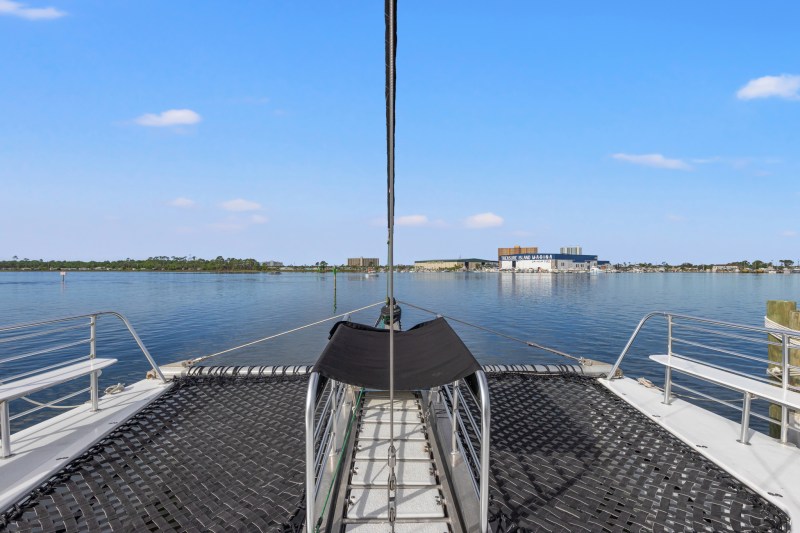View from the bow of a catamaran looking toward a marina on a clear day.