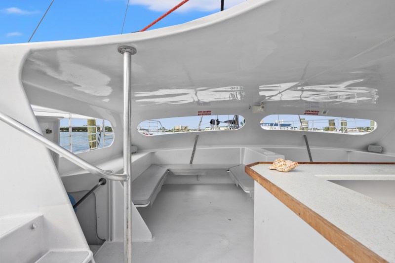 Interior of a boat with white seating and a countertop, ocean view through windows.