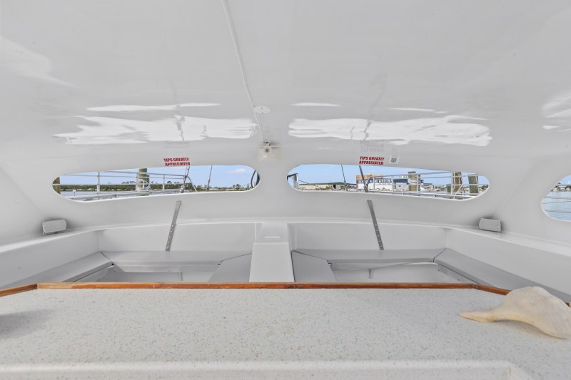 Interior of a boat cabin with shell on table and windows showing a marina view.