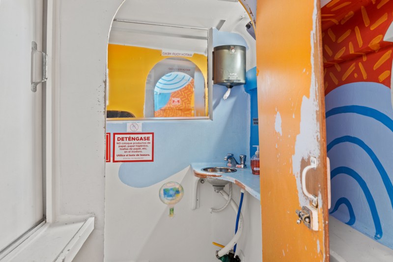 Colorful restroom interior with sink, mirror, and vibrant orange and blue patterns.