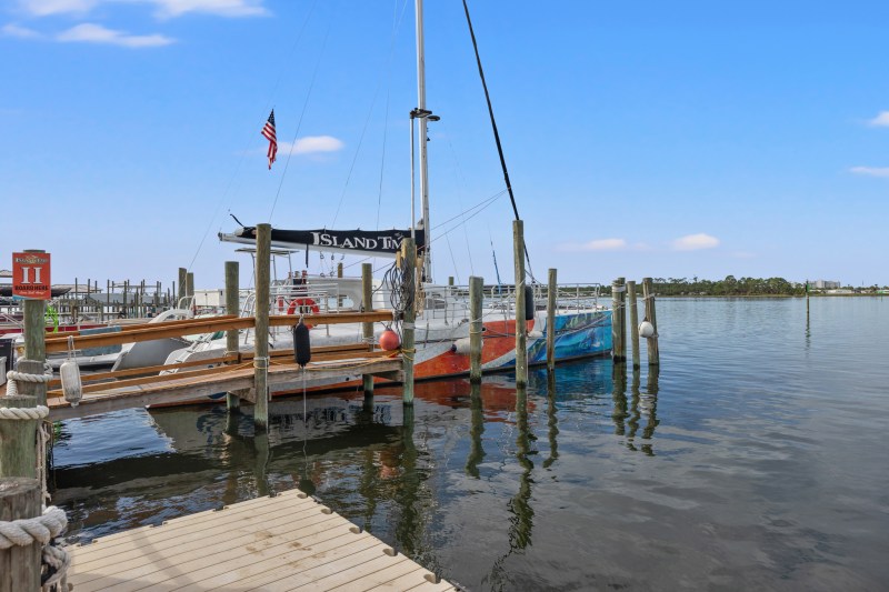 Docked sailboats at a pier with a clear blue sky and calm water.