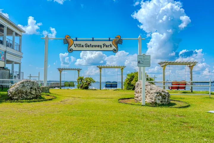 Villa Gateway Park entrance with seating areas and clear sky.