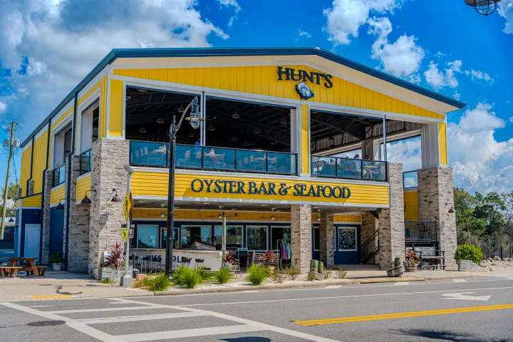 Two-story yellow seafood restaurant with outdoor seating on a sunny day.