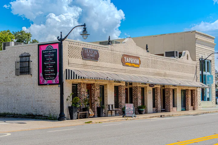 Street view of rustic white brick building with awnings under a blue sky.