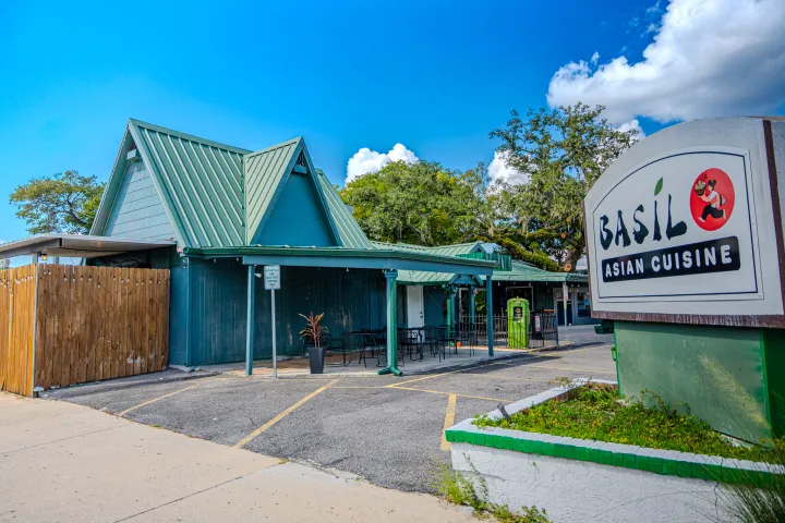 Restaurant with green roof and sign reading 'Basil Asian Cuisine' in parking lot.