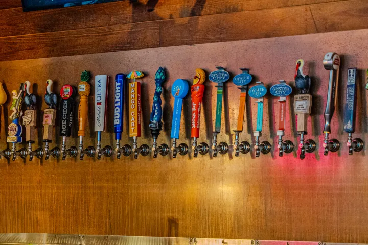 Row of colorful beer tap handles against a wooden background.