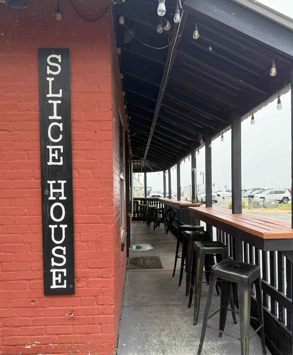 Red brick wall with 'Slice House' sign, outdoor seating with bar stools.