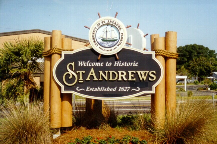Sign reading 'Welcome to Historic St. Andrews, Established 1827' with nautical design and foliage.